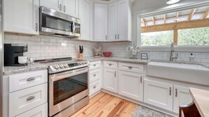 A modern kitchen with white cabinets, a stainless steel microwave, an oven, and a coffee maker. - Creekside screened porch, pet friendly, minutes to downtown Hayesville. Firewood (Hayesville)
