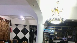 A hotel lobby with a check-in counter, a dining area with a table and chairs, and a decorative floor pattern. - Image Classic Hotel (Kwabenya)