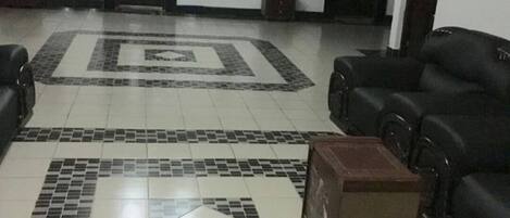 A lobby with a tiled floor, a chandelier, a reception desk, and a seating area with sofas.