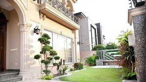 A well-maintained courtyard with a paved walkway, trimmed hedges, and a small lawn. - Spanish Villa/5 BHK/Raya Golf course & Cinema 2Kms (Lahore)