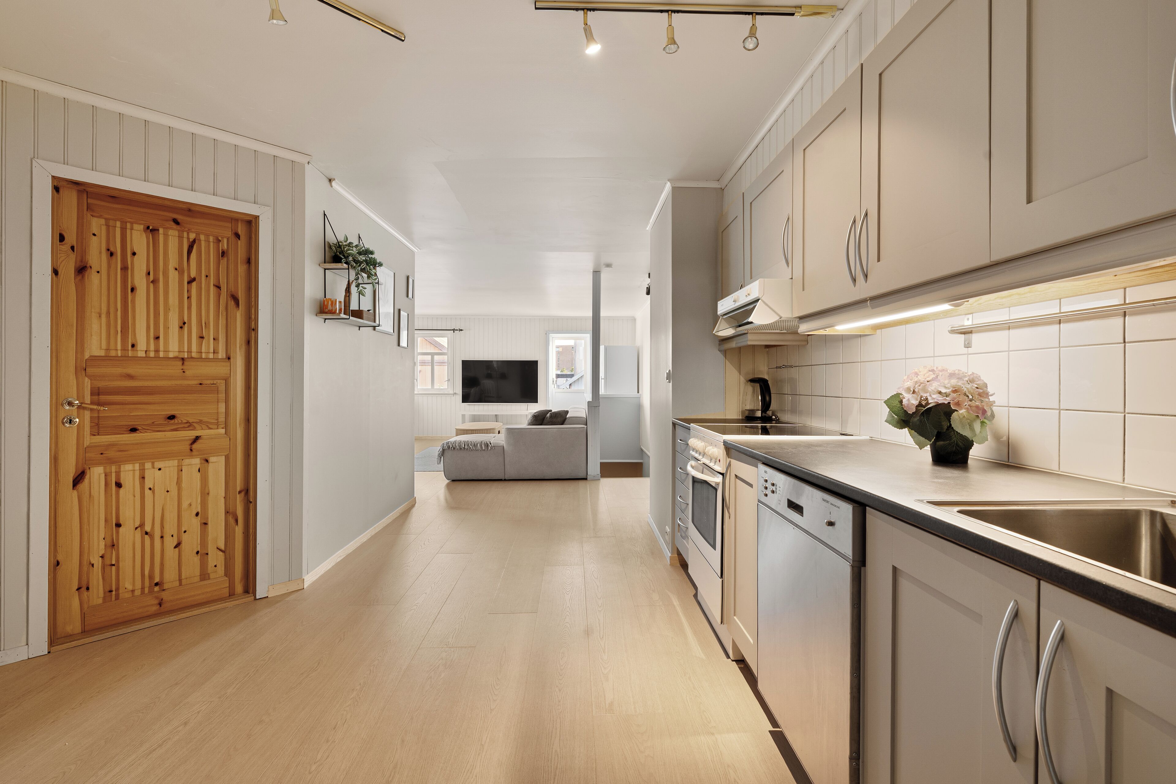 A modern kitchen with wooden cabinetry, a built-in oven, and a stainless steel sink.