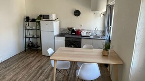 A compact kitchen with a wooden table and chairs, a microwave, a coffee maker, and a sink. - Large Studio 100m from the beach (Toulon)