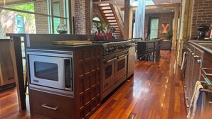 A kitchen with a large island, wooden flooring, and a brick wall. - 3-Bedroom, Outdoor Japanese Soaking Tub, Fire-Pit, originally built in 1890!   (Denver)
