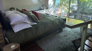 A modern bedroom with a large bed, a view of the outdoors, and a painting on the wall. - 3-Bedroom, Outdoor Japanese Soaking Tub, Fire-Pit, originally built in 1890!   (Denver)