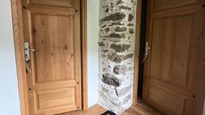 Esquina de una habitación con dos puertas de madera, una de ellas con una pared de piedra parcialmente visible.