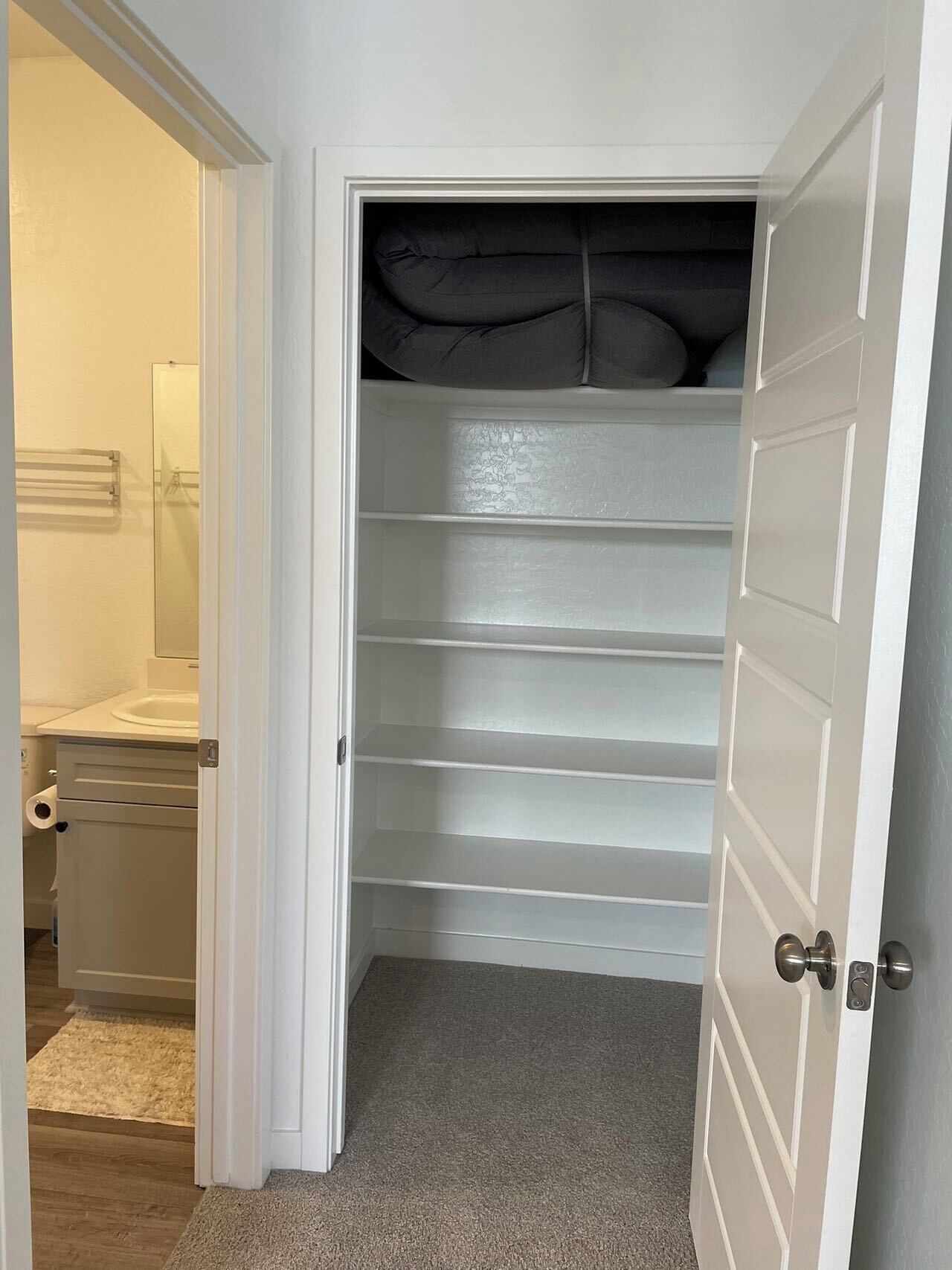 Um closet amplo com portas brancas, várias prateleiras e um espelho.