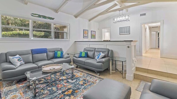 A modern living room with two grey sofas, a coffee table, and a patterned rug.