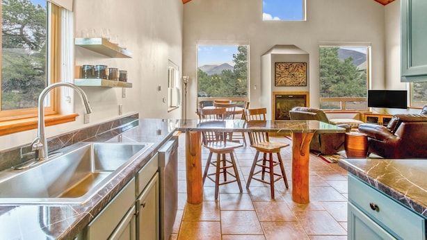 A modern kitchen with a large island, bar stools, and a dining area with a view of mountains.