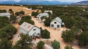 A residential area with multiple houses surrounded by trees and a mountainous backdrop.