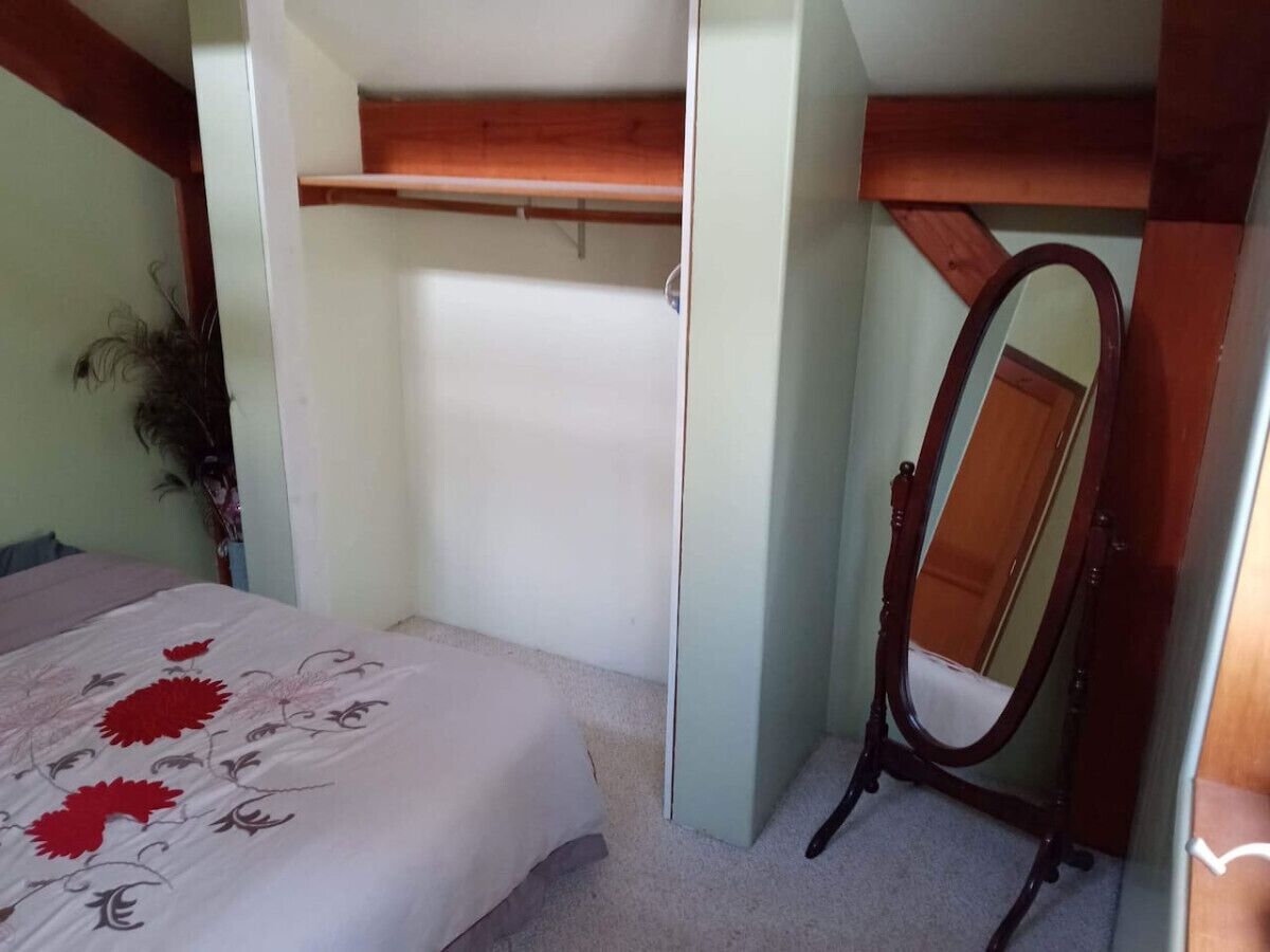 Un dormitorio con una cama, un estante de madera y un espejo.
