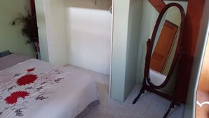 Une chambre à coucher avec un lit, une étagère en bois et un miroir.