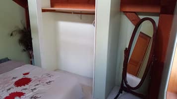 Un dormitorio con una cama, un estante de madera y un espejo.