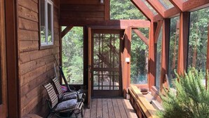 Une terrasse en bois avec un banc, une porte et une fenêtre.