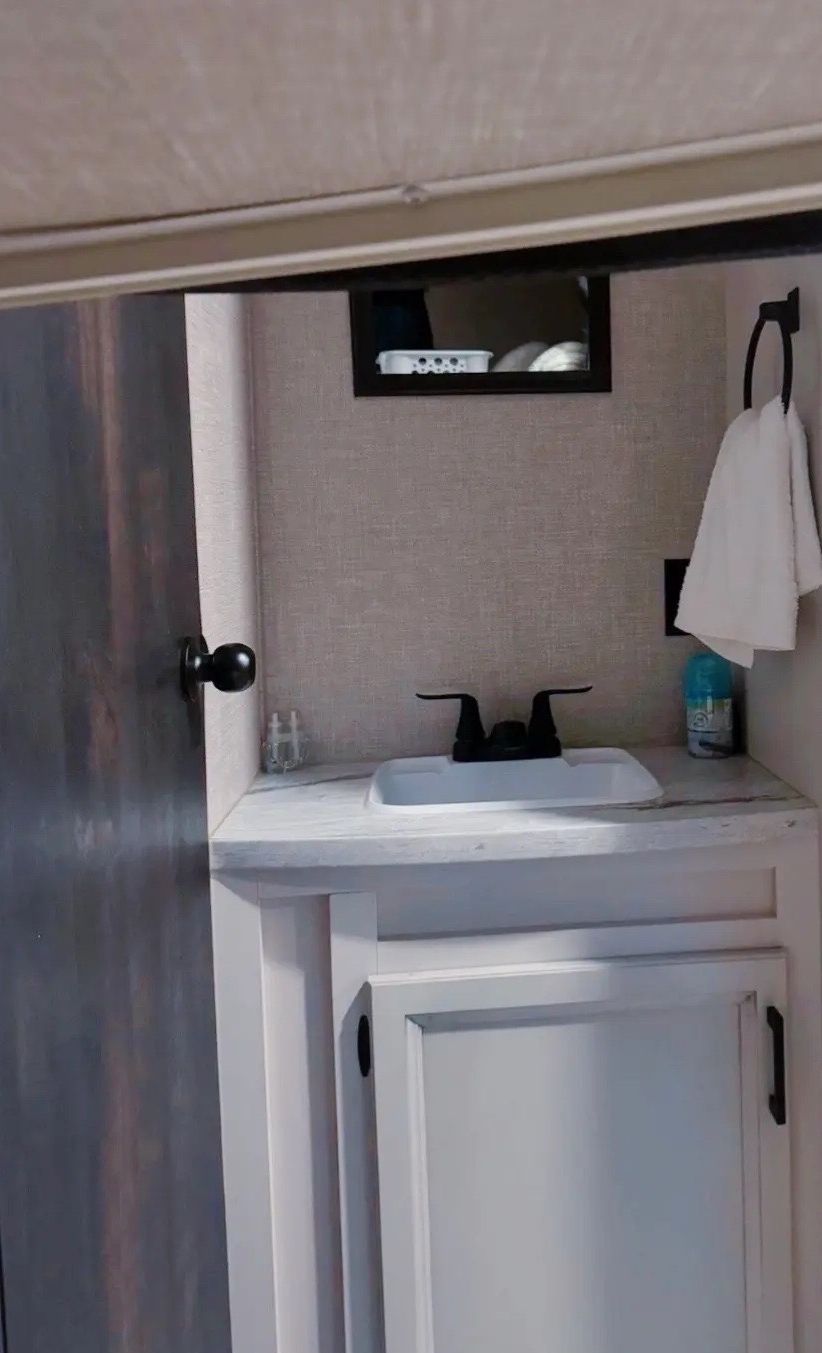 A bathroom with a white sink, a mirror, and a towel hanging on the wall.