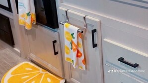 A kitchen with a stove, oven, and a sink. There are two towels hanging on the oven handle. - “RV Country Living” Glamping (Clewiston)