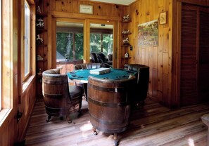 A wooden room with a pool table, leather chairs, and wooden barrels. - The Luxury Cabin at Deep Hollow (Narrowsburg)