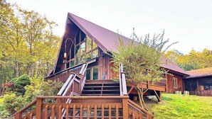 A wooden staircase leading to a building with large windows and a sloped roof. - The Luxury Cabin at Deep Hollow (Narrowsburg)