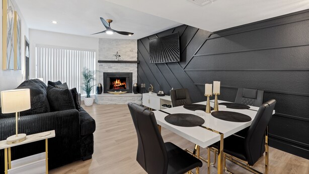 A modern living room with a fireplace, black and white furniture, and a dining area with a white table and black chairs.