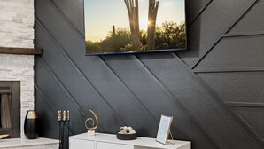 A modern interior with a white cabinet, a black wall with geometric patterns, and a framed picture of a sunset.