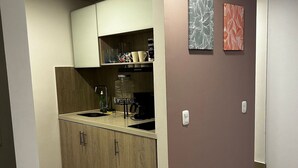 A compact kitchen with wooden cabinets, a built-in sink, and a countertop. There are two wall-mounted light switches and a shelf with kitchenware. - Loft Centro Internacional y Terraza 211 (Bogotá)