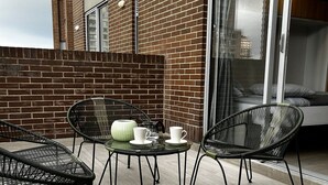 An outdoor patio with a brick wall, a glass door, and a table with chairs. - Loft Centro Internacional y Terraza 211 (Bogotá)