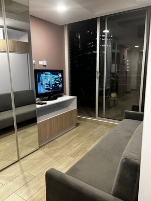 A modern living room with a flat-screen TV, grey sofas, and a wooden cabinet. - Loft Centro Internacional y Terraza 211 (Bogotá)