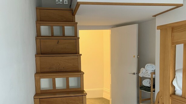A wooden staircase with glass panels leading to a loft bedroom with a pink bedspread. - Perfect Location next to bars & restaurants and 10 mins walk to Bournemouth pier (Bournemouth)