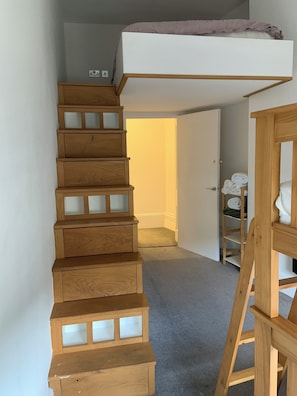 Staircase leads to a lofted sleeping area with a ladder for easy access.