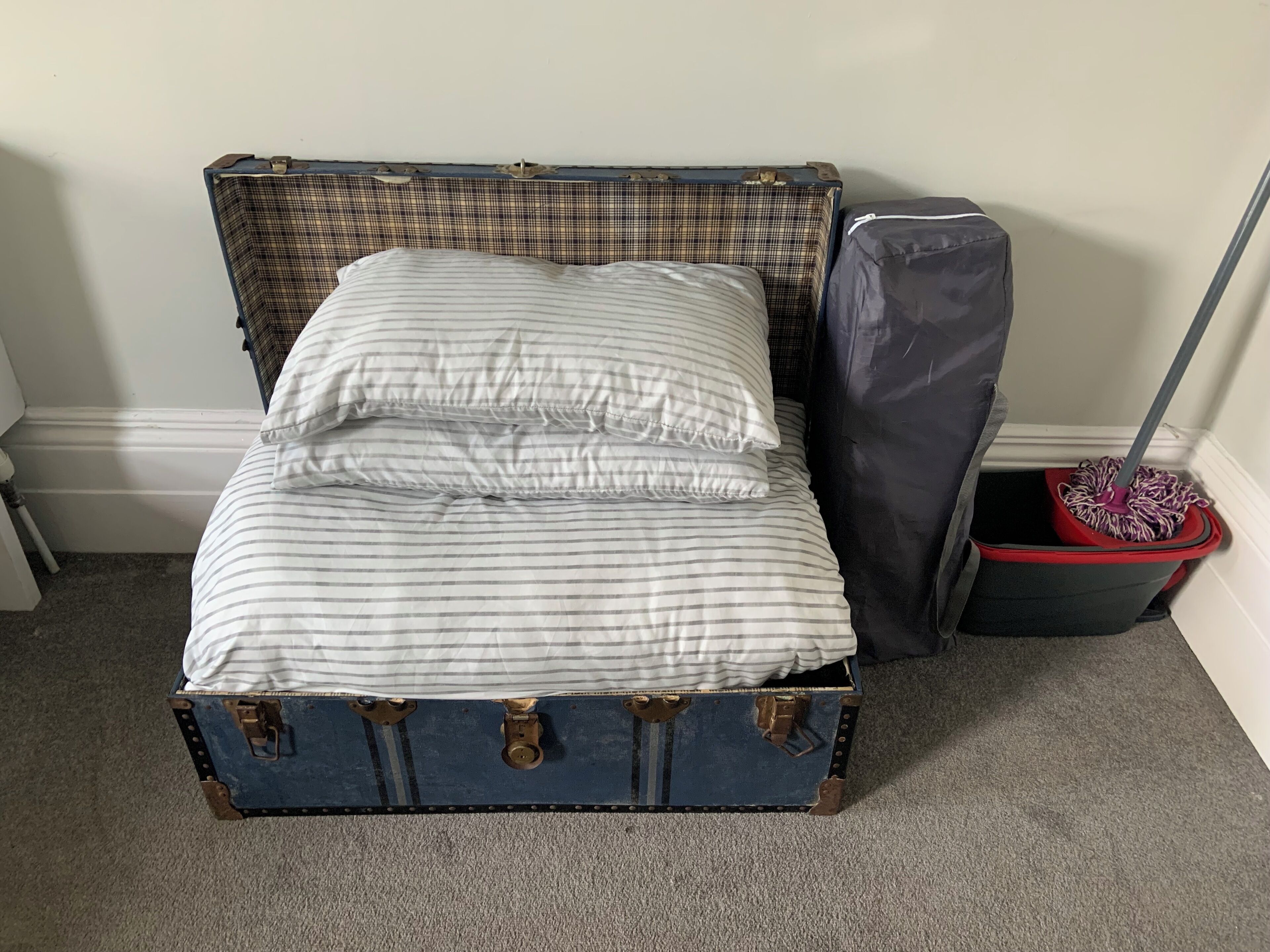 A bed with striped bedding in a room with a suitcase-style headboard.