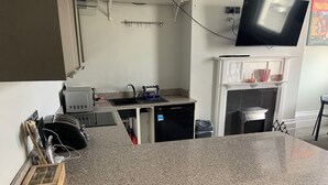 A kitchen with granite countertops, a dishwasher, a sink, and a television mounted on the wall. - Perfect Location next to bars & restaurants and 10 mins walk to Bournemouth pier (Bournemouth)