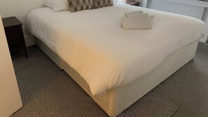 A neatly made bed with white bedding and two patterned pillows, a small bedside table, and a radiator under a window. - Perfect Location next to bars & restaurants and 10 mins walk to Bournemouth pier (Bournemouth)