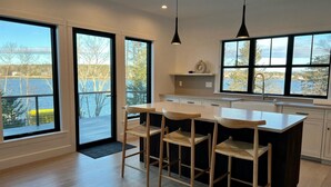 Eine moderne Küche mit großen Fenstern, einer zentralen Kochinsel mit Barhocker und Seeblick.