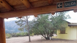 Un espacio al aire libre con una estructura de madera, una maceta roja y un cartel que indica una salida.