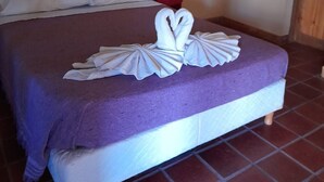 Una cama con una colcha morada, almohadas blancas y una presentación de toallas sobre la cama.