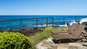 Ein Balkon mit Blick auf das Meer, ausgestattet mit zwei Korbstühlen und einem Fliesenboden.