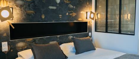 A modern bedroom with a large bed, two bedside lamps, and a wall mural of hot air balloons.
