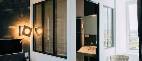 A modern bathroom with a large window, a sink, and a chair.