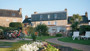 A stone building with a garden, outdoor seating, and bicycles. - les agapanthes (Ploubazlanec)