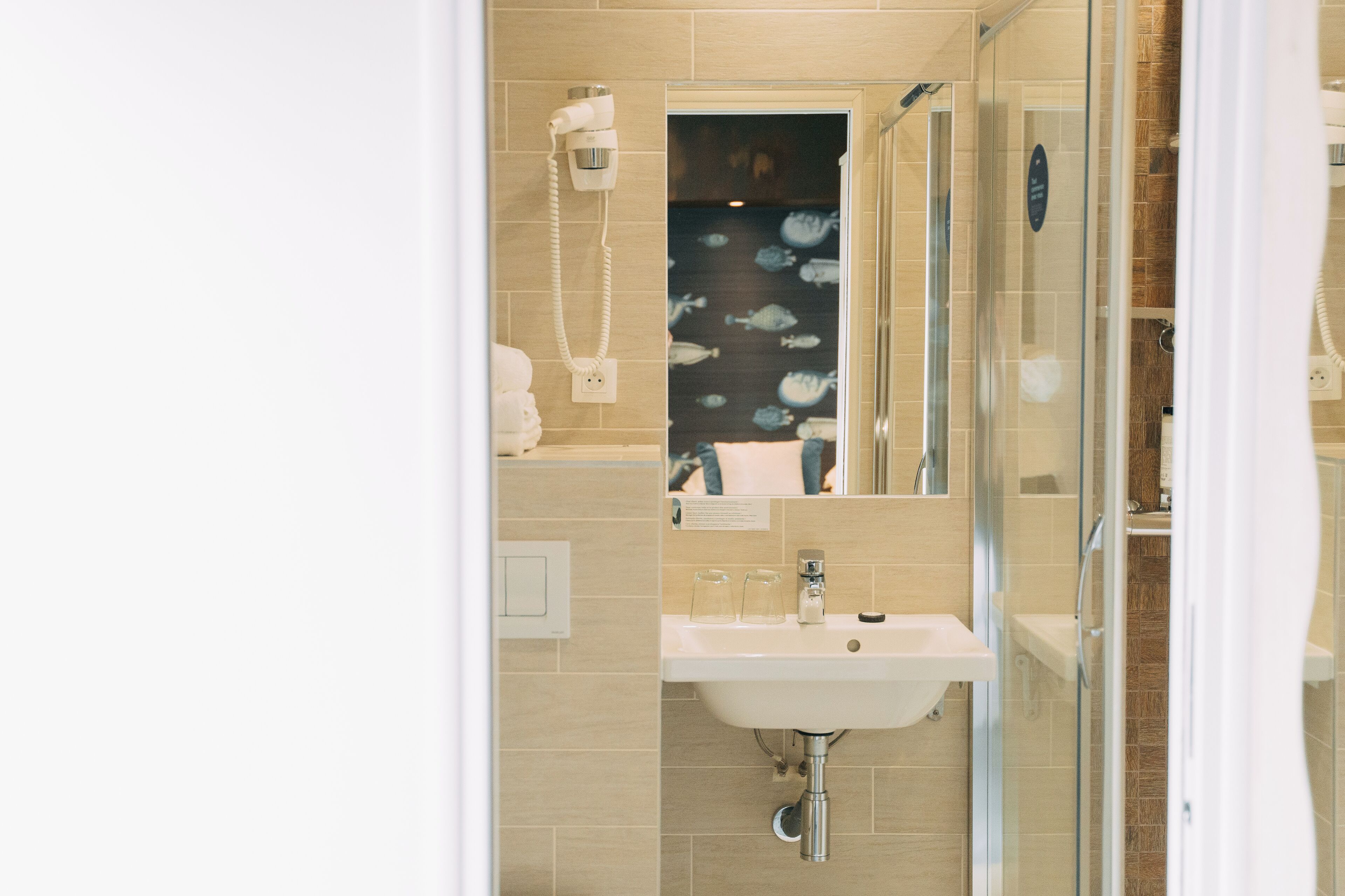 A bathroom with a glass shower enclosure, a sink, and a mirror.