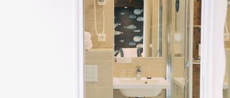 A bathroom with a glass shower enclosure, a sink, and a mirror.