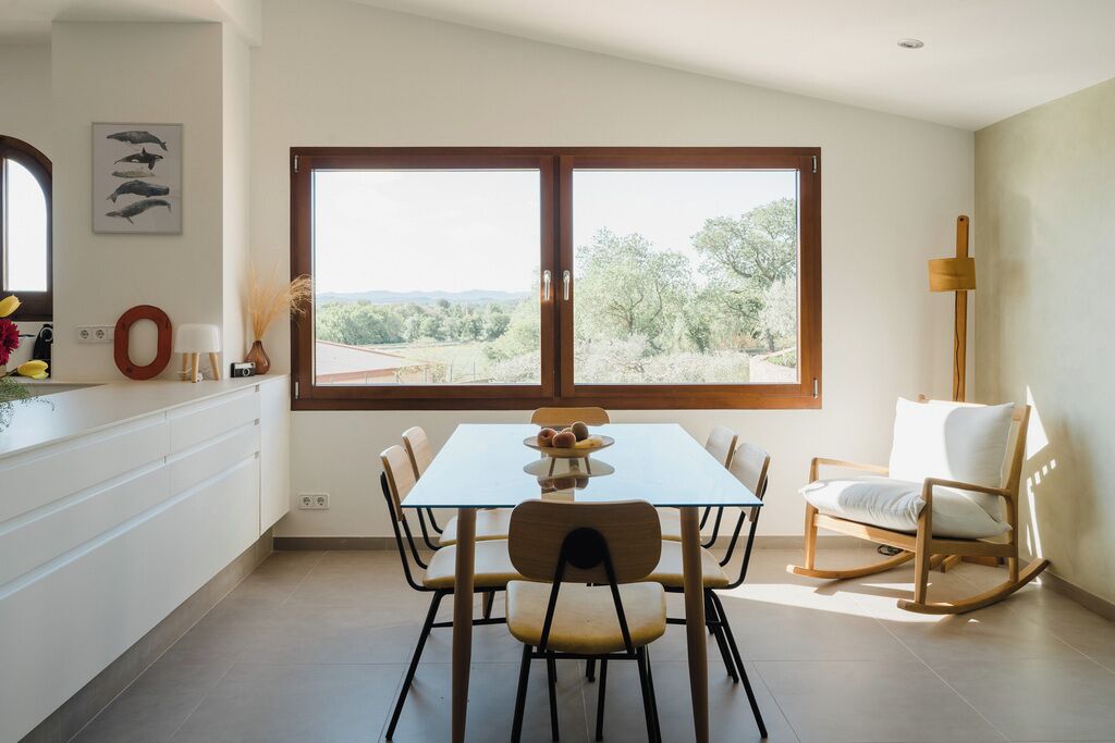 A dining area with a glass table, chairs, and a view of the outdoors.
