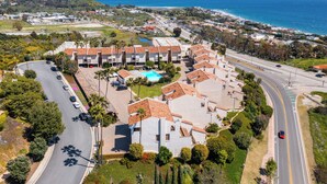 Zona residencial costera con piscina, edificios de varios pisos y una calle con vehículos.