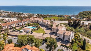 Zona residencial costera con piscina, varios edificios y vista al mar.