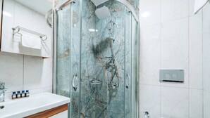 Un bagno moderno con doccia vetrata, lavabo bianco e piano in legno, e un water.