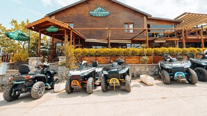 Un edificio in legno con un cartello che riporta “Mysia Olympos Hotel”. Quattro veicoli ATV parcheggiati davanti.