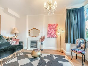 A living room with a black sofa, a patterned rug, a fireplace, a mirror, and a decorative wall piece.