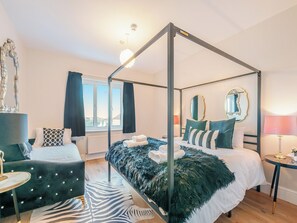 A four-poster canopy bed with a zebra-patterned rug, a round side table, and a mirror on the wall.