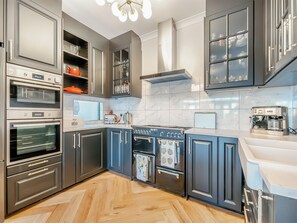 A modern kitchen with built-in ovens, a stove, and a coffee machine.