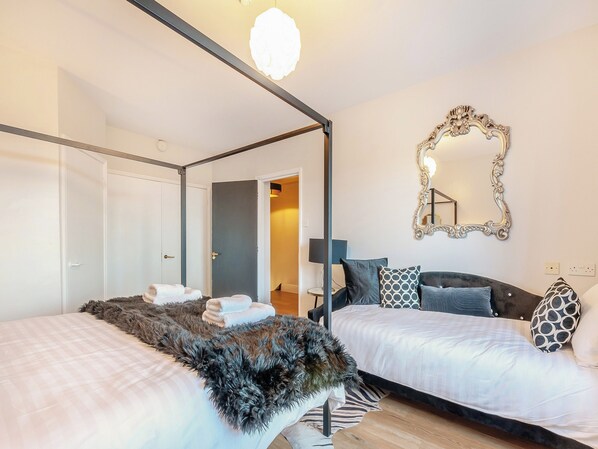 A modern bedroom with two beds, a large mirror, and a fur throw.