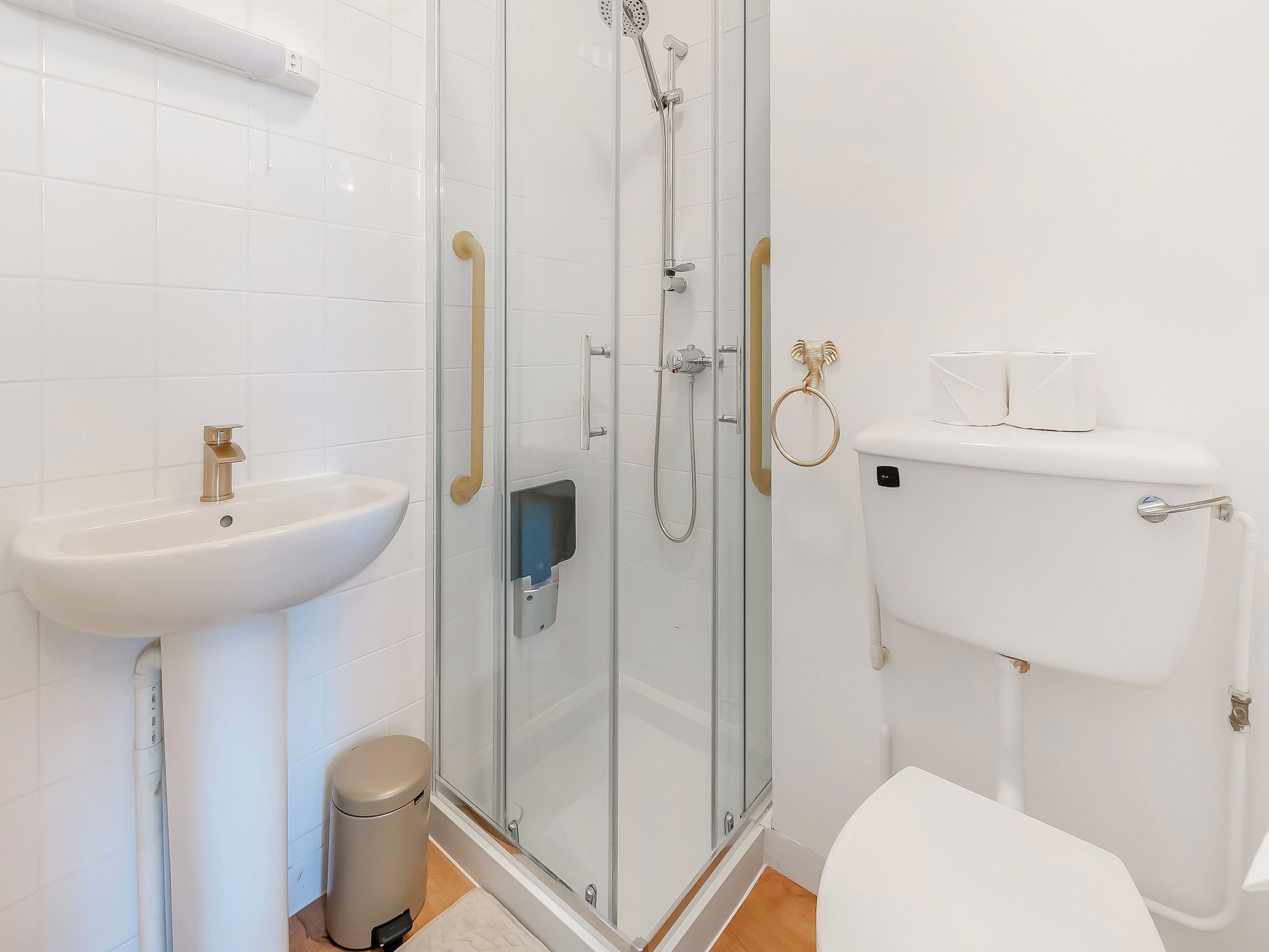 A bathroom with a glass-enclosed shower, a white sink, and a toilet.